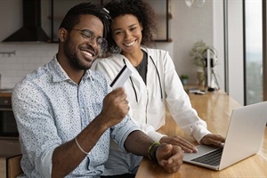 man holds credit card while sitting next to woman at computer