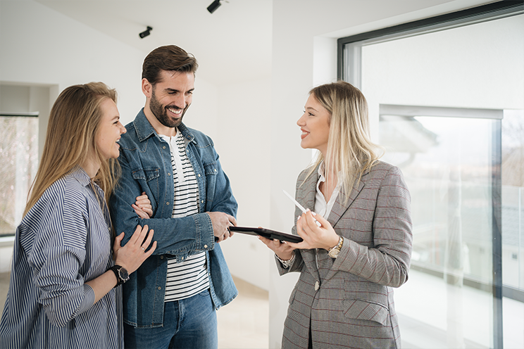 man and woman standing with realtor in empty home