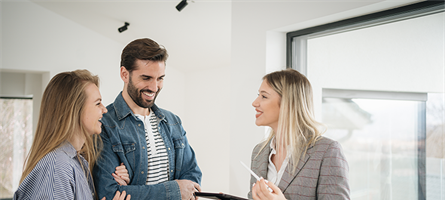 man and woman standing with realtor in empty home