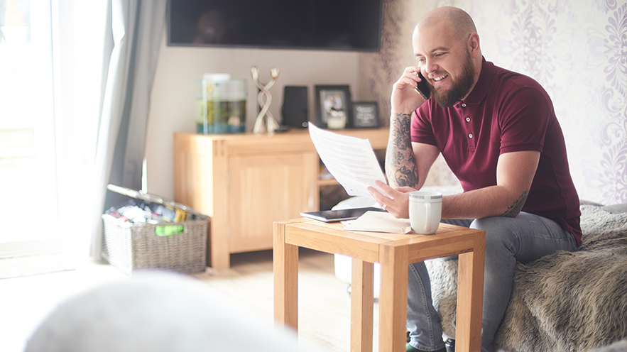 Man holds phone and papers