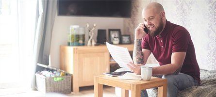 Man holds phone and papers