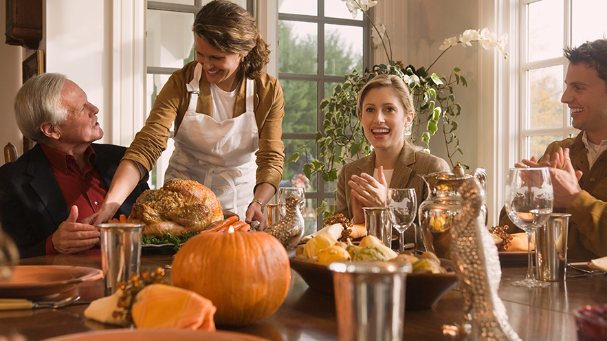 Family sitting around a table with pumpkins and food