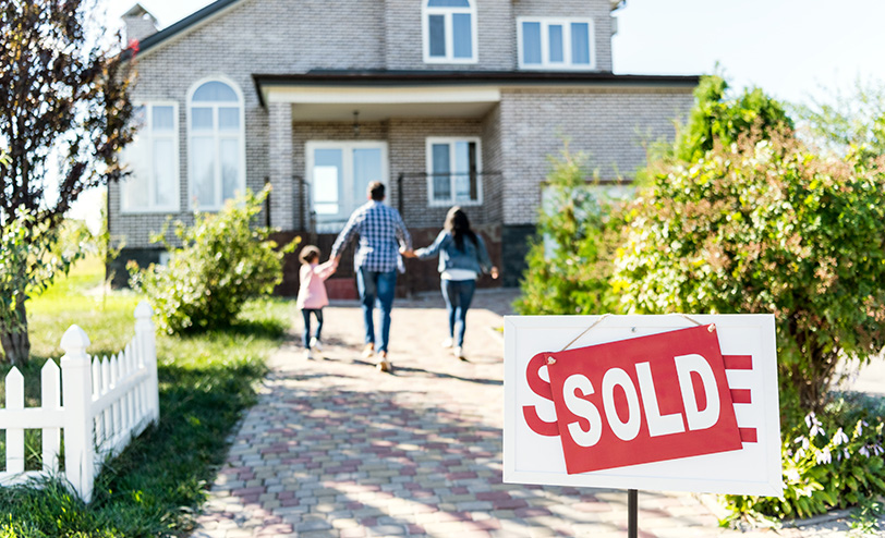 Family walks toward new home with sold sign at the forefront