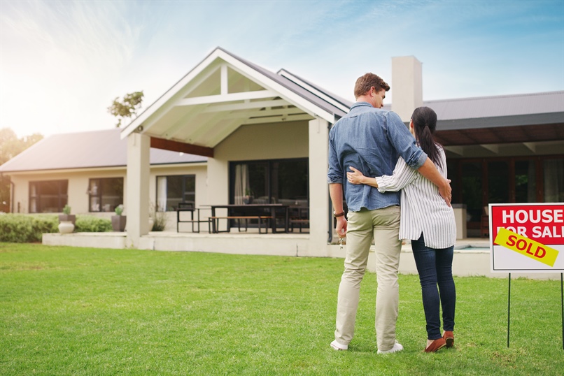 Man and woman embracing in front of house with a 