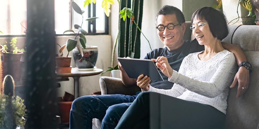 Man and woman sitting relaxed on couch on iPad