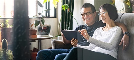 Man and woman sitting relaxed on couch on iPad