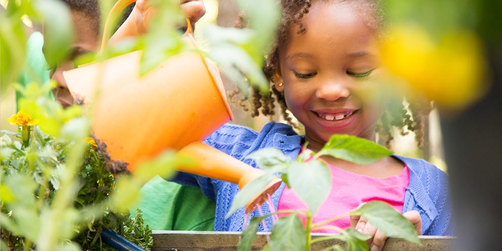 Little girl watering flowers and gardening