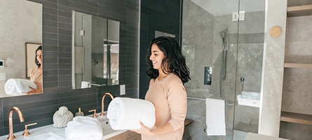 Woman brings freshly cleaned towels into a bathroom