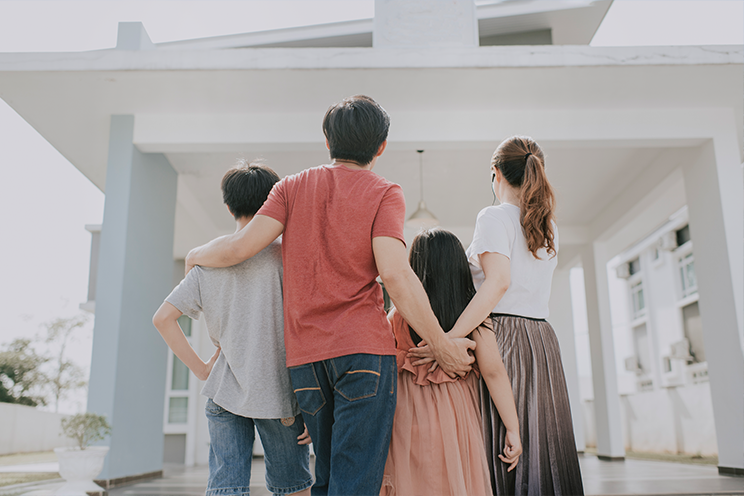 man, woman, boy and girl stare at house with backs turned away from camera