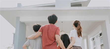 man, woman, boy and girl stare at house with backs turned away from camera