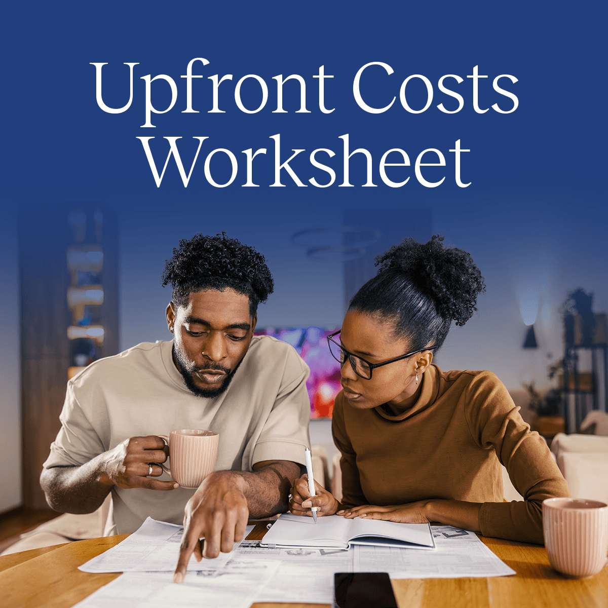 A couple sits at a desk reviewing financial documents